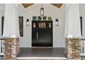 Close-up of the front door featuring a dark wood door, sidelights, and stone accents at 4642 Orchid Dr, Pine Lake, GA 30072