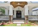 Inviting front porch with stone pillars, a dark front door with sidelights, and wood ceiling at 4642 Orchid Dr, Pine Lake, GA 30072