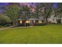 Inviting brick home featuring a green lawn, manicured hedges, and blue door at dusk at 2057 Cambridge Ave, Atlanta, GA 30337