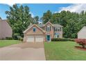 Traditional two-story brick home with a well-maintained lawn, mature trees, and a two-car garage at 5077 Wellisford Ct, Suwanee, GA 30024
