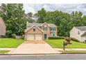 Lovely brick home with a two-car garage, lush green lawn, and mature trees in a quiet neighborhood at 5077 Wellisford Ct, Suwanee, GA 30024