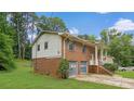 View of the side of a brick home featuring a covered front porch, and attached two-car garage at 115 Elizabeth Way, Ellenwood, GA 30294
