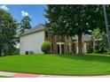 Brick two-story home showcasing a large lawn, mature trees, and traditional architectural design at 1055 Havenstone Walk, Lawrenceville, GA 30045