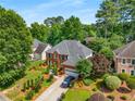 Aerial view of a two-story brick home with mature landscaping and a private, wooded backyard at 1490 Rivershyre Pkwy, Lawrenceville, GA 30043