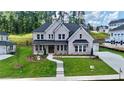 Beautiful two-story home with a light brick exterior, lush lawn, and dark metal awning accents at 2455 Bleckley Pl, Cumming, GA 30041