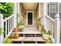 Inviting front porch featuring multiple potted plants and an American flag next to the front door at 1248 Rockview Ct, Loganville, GA 30052