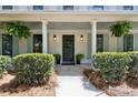 Inviting front porch with a stylish black door, hanging ferns, and manicured landscaping at 9165 Eves Cir, Roswell, GA 30076