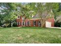 Traditional brick home with a well-kept lawn, featuring a two-car garage and mature trees at 2935 Abbottswell Dr, Alpharetta, GA 30022