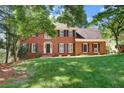 Beautiful brick home with black shutters and a green lawn, framed by mature trees at 2935 Abbottswell Dr, Alpharetta, GA 30022