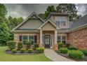 A brick home featuring manicured landscaping, dark shutters, and a concrete walkway at 9187 Plantation Cir, Covington, GA 30014