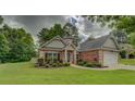 Beautiful brick home showcasing a lush green lawn and lovely front yard landscaping at 9187 Plantation Cir, Covington, GA 30014