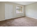 A simple, carpeted bedroom offers neutral tones, a window, and closet for a comfortable and functional space at 1513 Dupree Rd, Woodstock, GA 30189