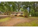 A quaint single-story brick house is nestled among mature trees in a serene landscape, creating a peaceful setting at 1513 Dupree Rd, Woodstock, GA 30189