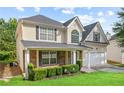 View of the charming two-story home featuring manicured lawn, covered porch, and a two-car garage at 273 Baywood Xing, Hiram, GA 30141