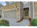 Close-up of the townhome showcasing stone accents, a gray siding exterior, and an inviting entryway with a dark-colored front door at 5965 Vista Brook Dr, Suwanee, GA 30024