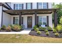 Inviting front porch with dark columns, fresh landscaping, and bench seating at 841 Keystone Dr, Woodstock, GA 30188
