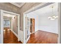 Hallway with hardwood floors, white trim, chandelier, and open doorway into the dining room at 5427 Trentham Dr, Atlanta, GA 30338