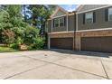 Townhome featuring a two-car garage, adjacent to a large concrete driveway, with well maintained landscaping at 4746 Highland Ave, Sugar Hill, GA 30518