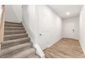 Bright hallway with wood-look flooring leading to the front door and features carpeted stairs to the second floor at 7254 Deering Court Lot 177, Douglasville, GA 30134