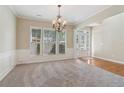 Inviting open-concept living area with neutral paint, modern chandelier, carpeted floors and wood accents at 1755 Rutland Pass Dr, Lawrenceville, GA 30045