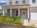 Inviting front porch with brick facade, white columns, and a vibrant wreath adorning the blue front door at 113 Poppy St, Mcdonough, GA 30253
