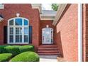 Close-up of the beautiful red brick front entrance with decorative shrubbery at 205 Finsbury Park Ct, Suwanee, GA 30024