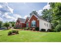 Well-maintained home with a green lawn, red brick exterior, and lush, mature landscaping at 205 Finsbury Park Ct, Suwanee, GA 30024