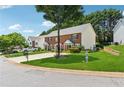 Street view of a brick townhome featuring a manicured lawn and mature shade trees at 3665 Magnolia Walk Trl, Cumming, GA 30040