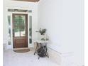 Inviting front porch with a wood door, white brick flooring, and a decorative sewing machine table at 688 Harmony Rd, Temple, GA 30179