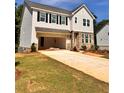Two-story house with an attached garage showcasing modern architectural design, a long driveway, and a green lawn at 7216 Eton Ln, Locust Grove, GA 30248
