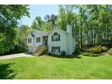 Two-story home with a well-maintained lawn, lush greenery, and a partial view of the deck at 8130 Estee Dr, Cumming, GA 30028