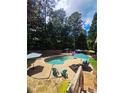 Backyard view of kidney-shaped pool with lounging area, umbrellas, and privacy fence surrounded by mature trees at 60 Stonehedge Dr, Buford, GA 30518