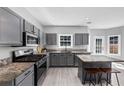 Modern kitchen with gray cabinets, stainless steel appliances, and stone countertops with eat in island at 5195 Oaks Landing Ct, Sugar Hill, GA 30518