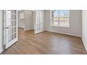 Bright, empty room with wood floors, white walls, baseboard trim, French doors, and a large window at 237 Arwen Drive Lot 61, Mcdonough, GA 30252