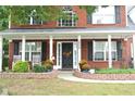 Inviting front porch with lush plants, stylish decor, and an elegant entrance to a brick home at 3824 Smith Creek Ct, Buford, GA 30519