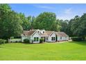 Charming white home boasts a lush green lawn, mature trees, and inviting curb appeal at 145 Deep Step Rd, Covington, GA 30014