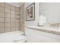 A clean, well-lit bathroom featuring tiled walls, a bathtub with shower, and a vanity with a granite countertop at 541 Fundao Ln, Lawrenceville, GA 30046