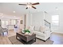 Bright living room featuring wood floors, a ceiling fan, and views into the kitchen and dining areas at 541 Fundao Ln, Lawrenceville, GA 30046