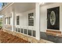 Covered front porch with white railings, stone foundation, and a stylish black front door at 2694 Hickory Valley Dr, Snellville, GA 30078