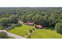 An aerial view shows the property with ample green space surrounded by mature trees and an open lot at 6674 Cowan Mill Rd, Winston, GA 30187