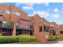 Exterior of brick townhomes with balconies, manicured hedges, and blue sky at 383 Ralph Mcgill Ne Blvd # J, Atlanta, GA 30312