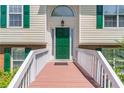 Close-up of the entrance featuring a vibrant green door and a charming wooden porch at 2325 Sailor Ln, Suwanee, GA 30024