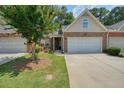 Beautiful townhome with a two-car garage, brick facade, lush lawn, and mature landscaping at 2521 Eden Ridge Ln # 7, Acworth, GA 30101