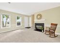 Cozy living room featuring neutral carpet, fireplace, mantel, large windows, and a rocking chair at 4177 Elder Ln, Duluth, GA 30096