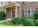 Close-up of the front entrance featuring a dark wood door, brick accents, and manicured shrubbery at 1786 Jameson Cir, Lawrenceville, GA 30043