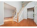 Light-filled foyer featuring hardwood floors, a staircase, and an open doorway to the living area at 3272 Monarch Pine Dr, Peachtree Corners, GA 30071
