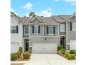Charming townhome with gray and white siding, a two car garage and lovely landscaping at 738 Woodstock Grove Dr, Woodstock, GA 30188