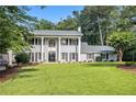 Two-story home featuring a manicured lawn, complemented by stately columns and black shutters at 6300 Blackwater Trl, Atlanta, GA 30328