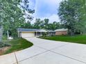 Single-story house with a long driveway, a well-maintained lawn, and an attached garage in a wooded area at 10381 E Cherokee Dr, Canton, GA 30115