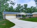 Single-story brick house with a long driveway and an attached garage surrounded by lush trees and greenery at 10381 E Cherokee Dr, Canton, GA 30115
